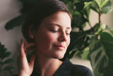 model wearing gold stud earrings that are cast from a pebble